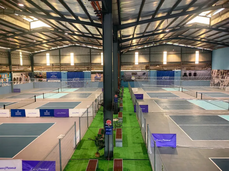 Overhead view of the indoor courts at Picklestop, with rows of blue pickleball courts under a steel roof