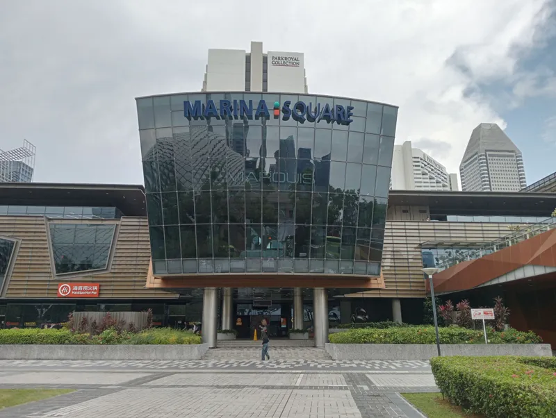 The glass-fronted main entrance of Marina Square mall in Singapore, with the MARINA SQUARE sign above the doors and hotel towers behind
