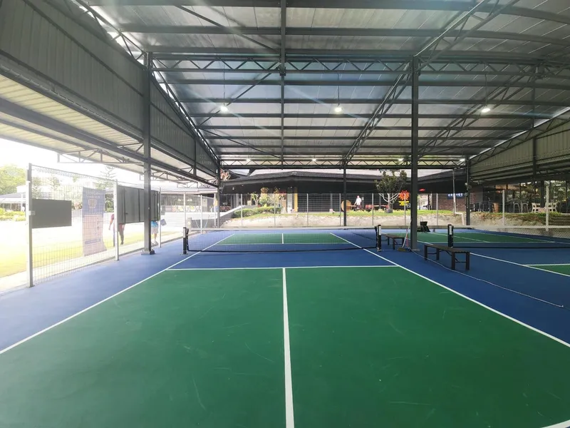 Two blue and green pickleball courts under a covered steel roof at Lakeside Pickle in Setia Eco Park